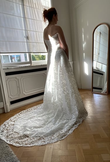a bride looking into the mirror for her final fitting of the wedding dress she has chosen for her