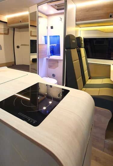 Zona de cocina, baño y asientos traseros de una furgoneta camperizada por Innovans