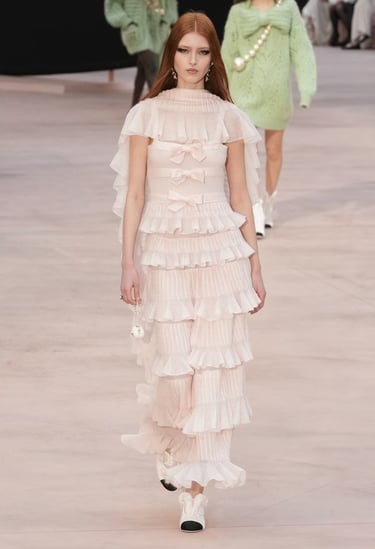 Model in pastel ruffled gown with layered bows from Chanel FW25/26.
