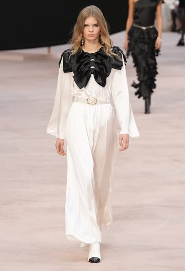 White jumpsuit with oversized black satin bows at Chanel FW25/26.