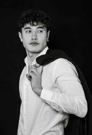 Man in smart casual wear taking a half-body selfie while looking away from camera in natural light