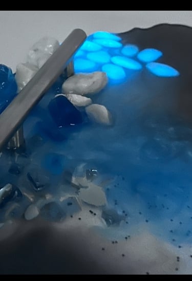 A round tray with silver handles with various rocks, blue ones glow in the dark