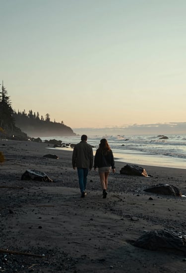 Wide cinematic shot of a couple walking along a rugged North American coastline, soft sunset lighting, charcoal and soft sand color palette, authentic and intimate mood.