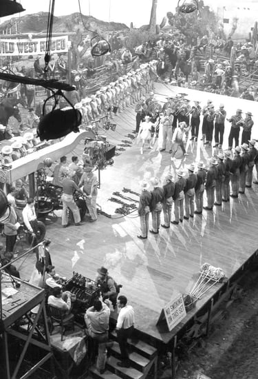 Behind‑the‑scenes shot of Berkeley filming Judy Garland and Mickey Rooney with fanned‑out cowboy dan