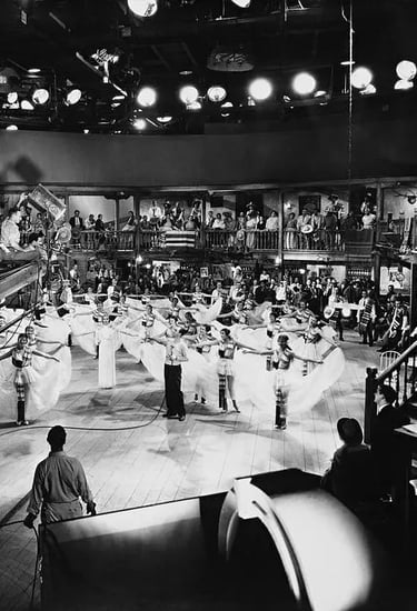 Berkeley on a crane with camera crew, filming white‑skirted dancers in geometric layout.