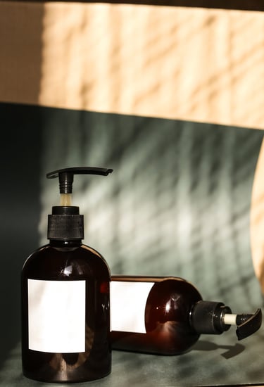 Amber glass cosmetic pump bottles with blank labels for organic skincare branding.