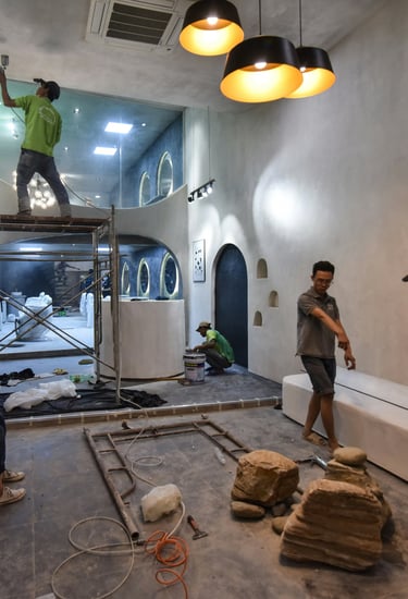 Construction workers performing interior renovations and painting in a modern building with scaffolding.