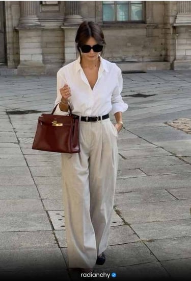 a woman in a white shirt and pants with a brown bag
