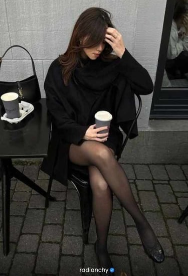 a woman sitting at a table with a cup of coffee