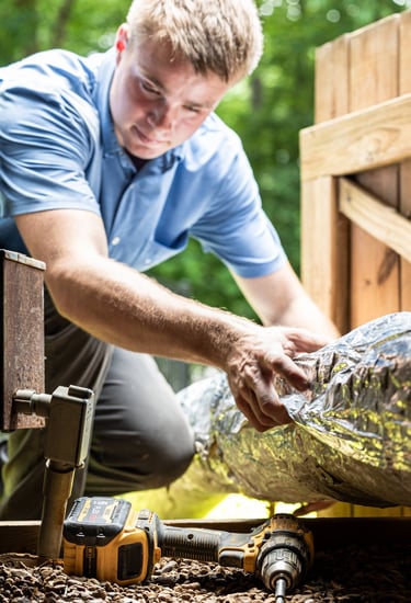 Nathan Smith moving a piece of Ductwork into a crawlspace