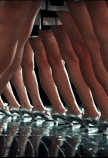 Homage scene from Ken Russell’s The Boy Friend (1971) with silver‑shoed dancers in wide‑leg stance.