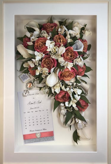 a Trailing view Style bouquet of flowers with keepsakes in a thin white frame