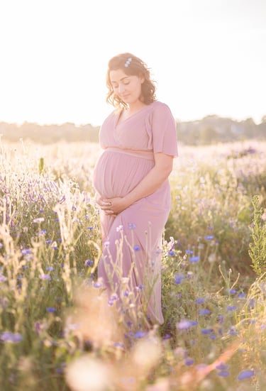 femme enceinte dans un champ de fleurs au coucher du soleil