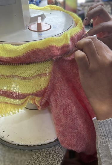 a person is sewinging a sweater with a yellow and red scarf