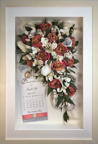 a Trailing view Style bouquet of flowers with keepsakes in a thin white frame