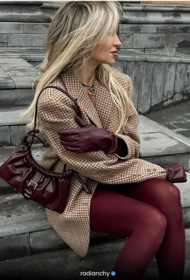 a woman in a coat and gloves sitting on a bench