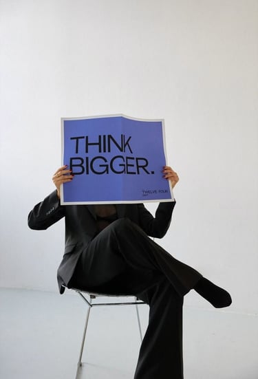 Entrepreneur holding a “Think Bigger” sign symbolizing business growth and digital transformation fo