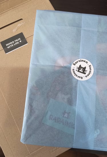 Handmade item wrapped in blue tissue paper with a Rarainka cat logo sticker.