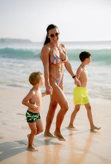 Mother walking with her children along the shoreline during a family photography session at Dreamland Beach Bali.