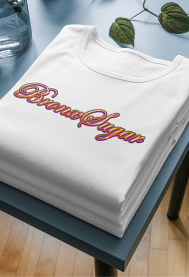 Folded white t-shirt featuring a colorful retro Bronx Sugar script logo on a blue side table.