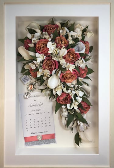 a Trailing view Style bouquet of flowers with keepsakes in a thin white frame