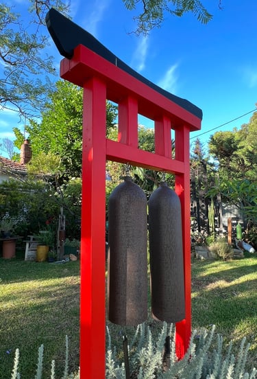 torri gate with two gongs in garden setting