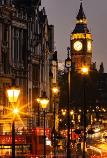 Night view of Big Ben and a red double-decker bus on a glowing London street with streetlights.