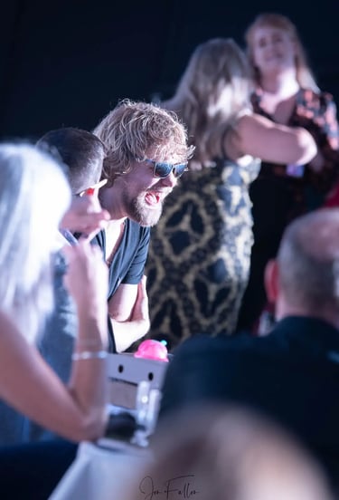 Smiling man with blonde hair and sunglasses enjoying a social event or party with friends.
