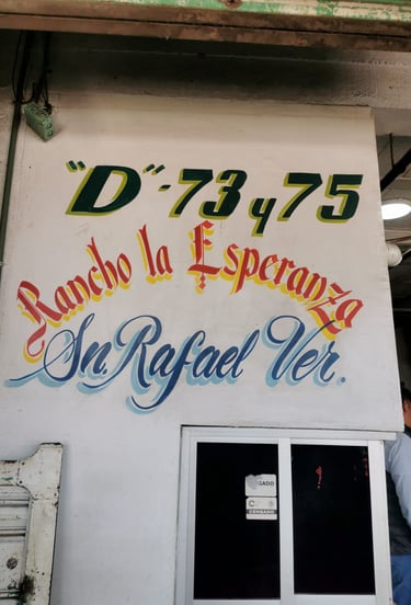 Letrero pintado en la pared de un negocio: "D-73, 75, Rancho la Esperanza, Sn. Rafael Ver