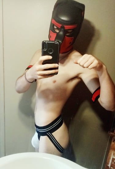 A Man posing for a selfie in a jock and pup mask.