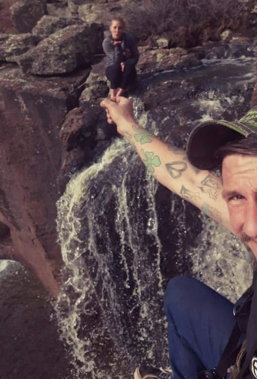 a man with a tattoo on his arm and a woman sitting on a rock