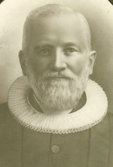 A man with a white ruffled collar and a white beard and mustache, black and white