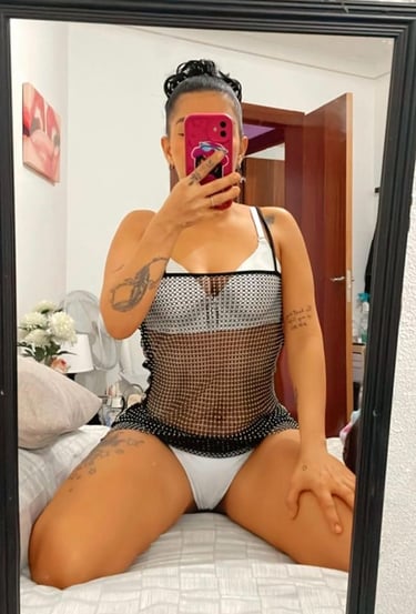 chica escort en Sabadell haciendo un selfi en una cama en ropa interior blanca y con las piernas abiertas