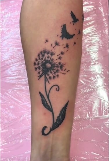 a tattoo of a dandela flower on a woman's forearm