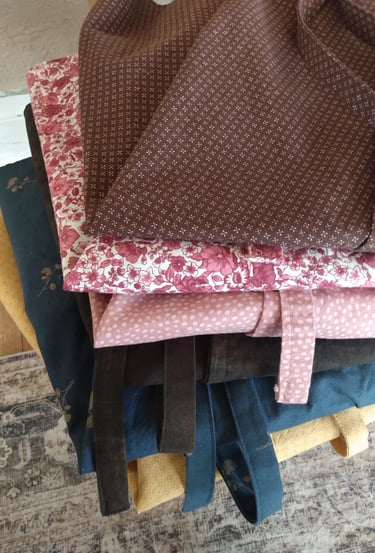 A stack of neatly folded wrap skirts made with love from assorted pretty cotton calico fabrics