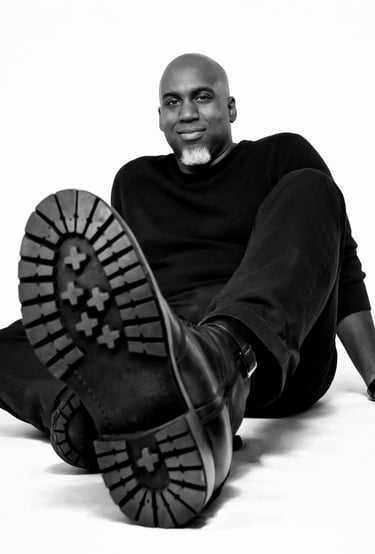 Lee A Jones in all black sitting on the floor with black boots