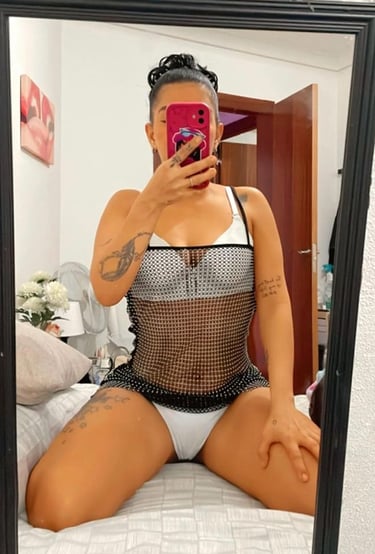 chica escort en Sabadell haciendo un selfi en una cama en ropa interior blanca y con las piernas abiertas