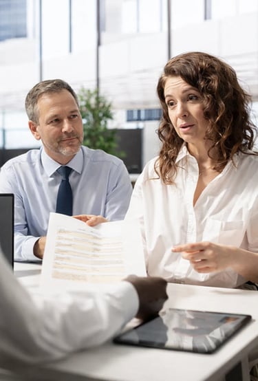 Professional business consultants reviewing legal documents and contracts with a client in a modern office.