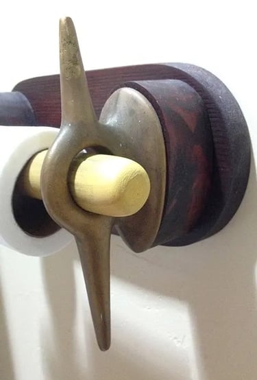 Side view of a toilet paper holder made of two brass cleats.