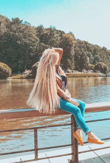 a woman sitting on a bench in front of a lake