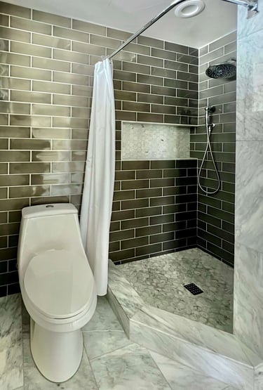 A bathroom with marble floor tile, and full height grey subway wall tile.
