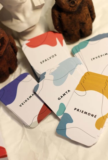 Saviterapijos kortelės kūrybiškumui išdėstytos ant balto popieriaus.