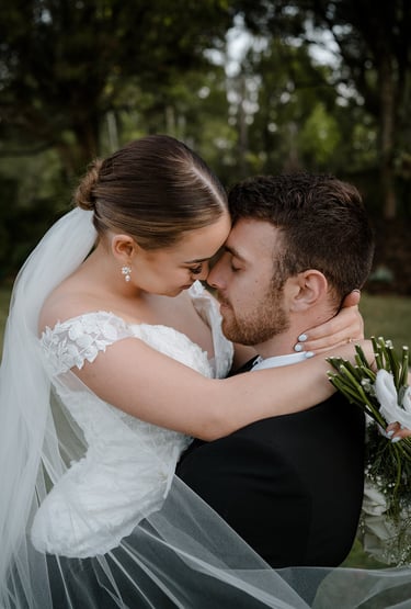 a bride and groom kissing in a field