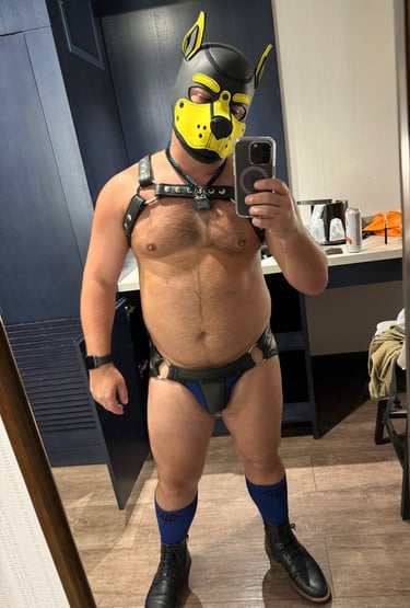 Full body image of a man in pup mask and leather gear.