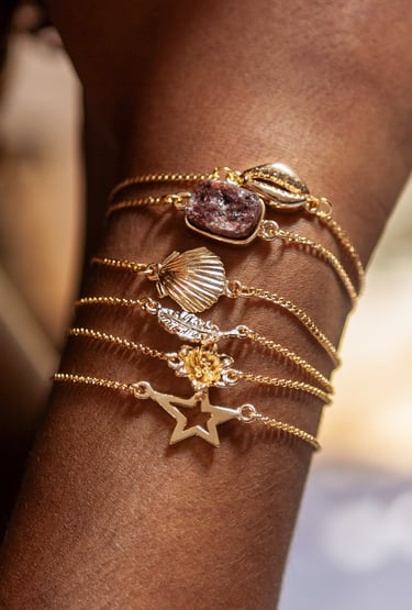 o braço de uma mulher com pulseiras pratas e douradas. 