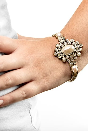 a mão de uma mulher usando uma pulseira com pérolas