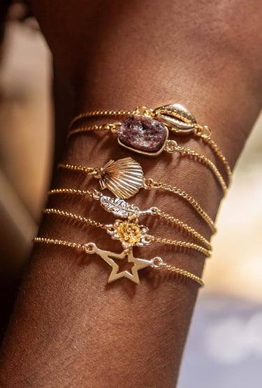 o braço de uma mulher com pulseiras pratas e douradas.
