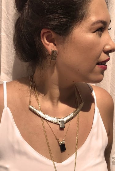 uma mulher veste uma blusa branca com um mix de colares com cristas e obsidiana negra