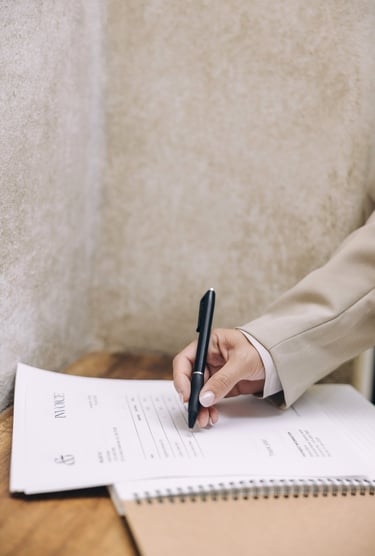 A woman's hand holding a pen and writing on an invoice on top of an open notebook