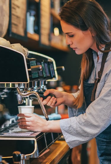 Femme debout devant une machine à café